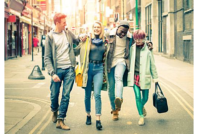 Fröhliche, multiethnische Freunde, die bei Shoreditch in London auf Brick Lane spazieren gehen