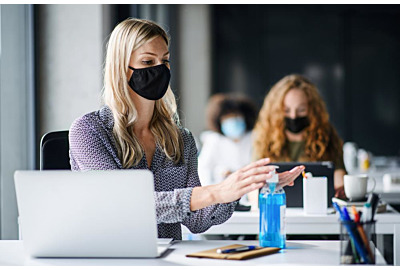 Junge Frau mit Gesichtsmaske zurück am Arbeitsplatz 